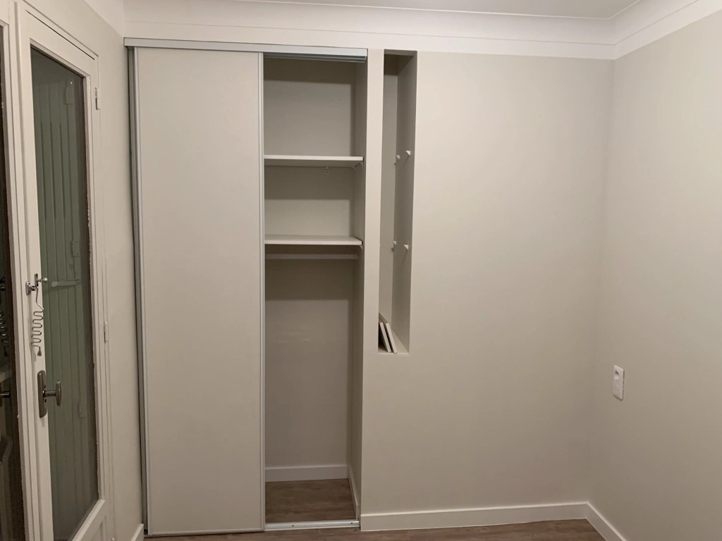 Rénovation complète appartement - photo après rénovation montrant l'aménagement du placard avec pose de l'encadrement et des portes et de la niche de la chambre